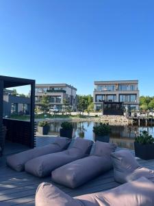 a row of pillows sitting on a deck near a body of water at Venedų apartament, Mano Jūra 2, Kunigiškiai in Palanga