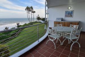a balcony with a table and chairs and the ocean at 25 Chaka's Cove in Ballito