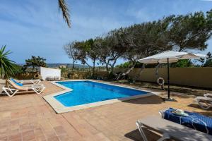 a swimming pool with an umbrella and some chairs and an umbrella at Ponent in Es Caló