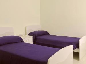 2 Betten in einem Zimmer mit lila Bettwäsche in der Unterkunft Casa Loredana in Putignano