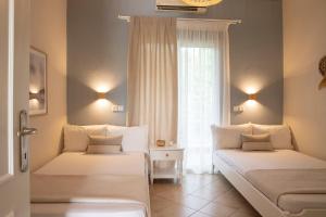 two beds in a room with a window at Elena luxury living in Paralía Skotínis