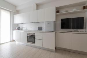 eine weiße Küche mit weißen Schränken und einem Flachbild-TV in der Unterkunft Casa Aleardi grazioso e nuovissimo monolocale con balcone in Pesaro
