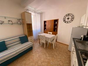 eine Küche und ein Esszimmer mit einem Tisch und einer Uhr in der Unterkunft Luisa Solferino 2 in Porto Azzurro