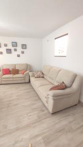 ein weißes Wohnzimmer mit 2 Sofas und Holzboden in der Unterkunft Il Tartarughino in Nettuno