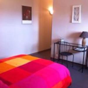 1 dormitorio con cama colorida y escritorio en Les Amandiers, en Draguignan