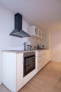 a kitchen with white cabinets and a stove at Koselig studioleilighet i Sandnes sentrum in Sandnes