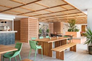 a restaurant with wooden tables and green chairs at Hotel Vibra Algarb in Playa d'en Bossa