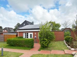 una casa de ladrillo rojo con techo negro en Bungalow *Ual Welhüs*, en Norddorf