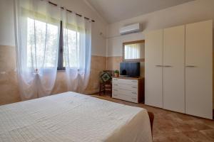 a bedroom with a white bed and a television at Casa Vacanza Baratz 4 in Alghero