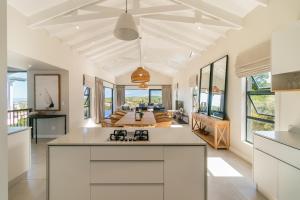 a kitchen with white cabinets and a living room at Pezula- Luxury Golf Retreat FC4 in Knysna
