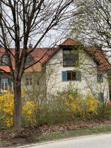 a white house with a tree and yellow flowers at Ferienwohnung 2 in Huglfing im Herzen vom 5 Seen Land Oberbayern in Huglfing