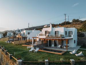 a large white house with a yard with chairs at Etesian Villas in Batsi