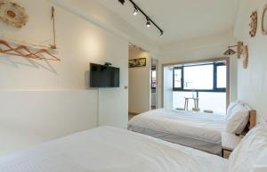 頭城的住宿－幸福海衝浪民宿，一间卧室设有两张床,墙上配有电视。