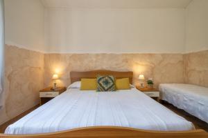 a bedroom with a large white bed with two lamps at Casa Vacanza Baratz 3 in Alghero