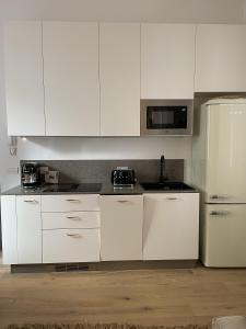 een keuken met witte kasten en een witte koelkast bij Studio Apartment Old Town Riva in Riva del Garda