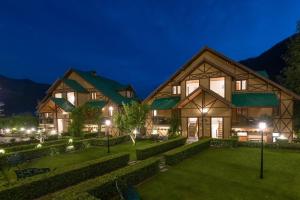 a large wooden house with a green yard at night at The Anantmaya Resort in Manāli