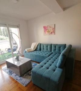 een woonkamer met een blauwe bank en een salontafel bij Apartman Dionis Centar in Trebinje