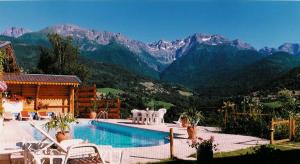a swimming pool with chairs and mountains in the background at Chalet la Colombière in Sainte-Agnès