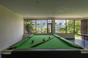 una mesa de billar verde en una habitación con ventanas en The Anantmaya Resort, en Manali