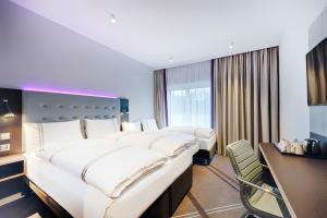 a hotel room with two beds and a desk at Premier Inn Regensburg City Centre in Regensburg