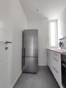 einen Kühlschrank aus Edelstahl in einer weißen Küche in der Unterkunft 'BRIGHT 29' schöne, ruhige Innenstadtlage in Bielefeld, 400 m bis Klinikum Mitte, Smart TV, WLAN in Bielefeld