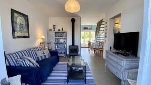 un salon avec un canapé bleu et une télévision dans l'établissement La Graveline, au Crotoy