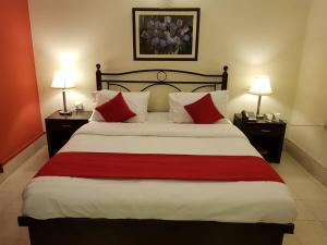 a bedroom with a large bed with red pillows at Herfa INN Hotel Lahore in Lahore