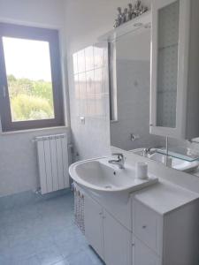 uma casa de banho branca com um lavatório e um espelho em Gheppio - Case Vacanze del Falco em Amelia