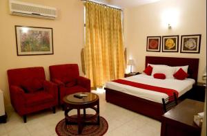 a hotel room with a bed and a red chair at Herfa INN Hotel Lahore in Lahore
