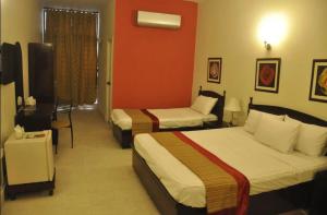a hotel room with two beds and a red wall at Herfa INN Hotel Lahore in Lahore