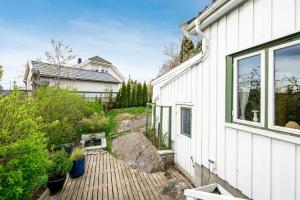 una terraza de madera junto a una casa blanca en Enebolig sentralt i Arendal., en Arendal