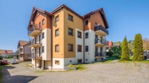 um edifício de apartamentos com varandas e um parque de estacionamento em Apartamenty Sun & Snow Gdańska II em Krynica Morska