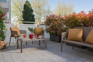 a patio with chairs and tables and potted plants at Nido Suite & Apartments in Cesenatico