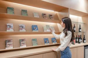 a woman is looking at a shelf with wine bottles at The Hyoosik Aank Hotel Cheongju Uam 2nd Branch in Cheongju