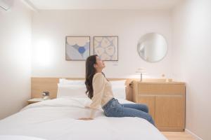 清州市Aank Hotel Cheongju Uam 2nd的女人坐在床上