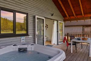 a large bath tub sitting on a deck with a table at Woodpecker Lodge, Redlake Farm nr Glastonbury in Somerton