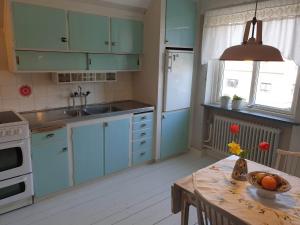 a kitchen with blue cabinets and a table with flowers on it at Egen ovanvåning i charmig villa nära havet in Ystad