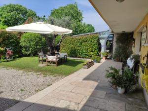 un patio con sombrilla, mesa y sillas en COUNTRY HOUSE CASAMIRIAM en Mirano