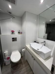 La salle de bains blanche est pourvue de toilettes et d'un lavabo. dans l'établissement Last Minute Herzliya, à Herzliya