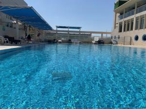une grande piscine bleue en face d'un bâtiment dans l'établissement Last Minute Herzliya, à Herzliya