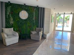 a lobby with two chairs and a wall covered in ivy at Last Minute Herzliya in Herzelia 