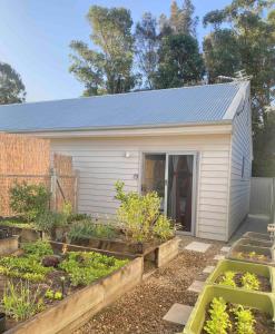 a small white shed with some vegetables in a garden at GARDEN CUBBY - The Lakeside Haven in Lake Illawarra