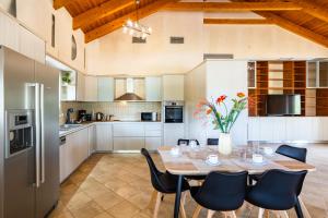 マラトポリスにあるEntheon Olive Villas - Poolside Retreatsの木製テーブルと椅子付きのキッチン、白いキャビネット付きのキッチン