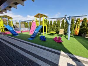 a playground with slides and play equipment on a lawn at Apartamenty Polanki 2 - Sauna, Jacuzzi, Podgrzewany Basen in Łeba