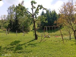 a playground in a field with a tree and swings at Kuca za odmor Braco in Donji Zvečaj