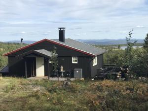 a black house with a table in front of it at Cabin in the Mountain, Outstanding View & Solar Energy in Vollen