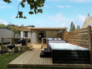 una terraza con bañera de hidromasaje y una casa en Camping Kost Ar Moor en Fouesnant