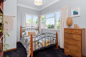 a bedroom with a bed and a dresser and windows at Live Large in the Village in Havelock North +15 photos