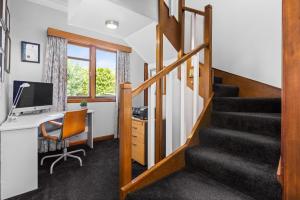 an office with a desk and a computer and stairs at Live Large in the Village in Havelock North