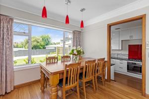 a kitchen and dining room with a wooden table and chairs at Live Large in the Village in Havelock North